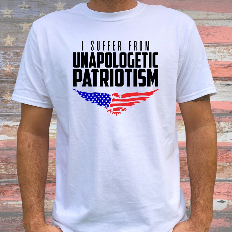 Op de afbeelding: Wit T-shirt met een zwarte adelaar afbeelding en de tekst "I suffer from unapologetic patriotism". De adelaar is gemaakt van de Amerikaanse vlag.