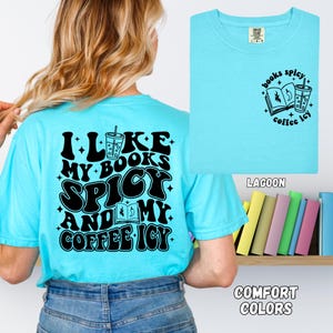 May include: A light blue t-shirt with the text "I like my books spicy and my coffee icy" on the back. The front of the shirt has a smaller graphic with the words "books spicy coffee icy". The shirt is labeled "Lagoon" and "Comfort Colors".