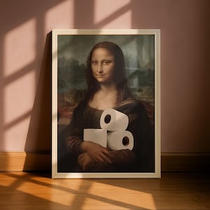 May include: A framed print featuring a classic portrait of a woman with dark hair and a dark dress, holding a stack of three white toilet paper rolls in her hands. The artwork is enclosed in a simple, light-coloured rectangular frame.
