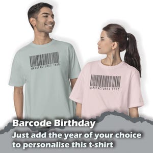 May include: Two t-shirts featuring a barcode design with the text "MANUFACTURED" followed by a year. The t-shirt on the left is light blue and the t-shirt on the right is pink. The text below the image reads "Barcode Birthday Just add the year of your choice to personalise this t-shirt."