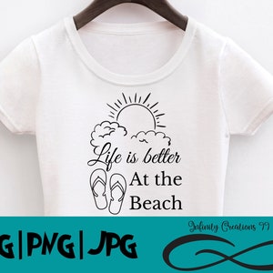 Op de afbeelding: Wit T-shirt met een zwart grafisch ontwerp met de tekst "Life is better at the beach". De grafiek bevat ook een zon, wolken en slippers.