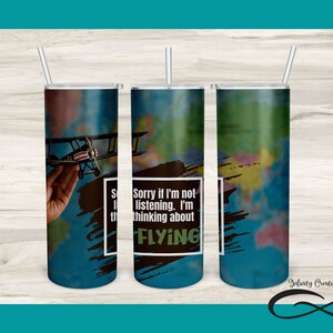 Könnte beinhalten: Ein Sublimationsdesign für einen 20 Unzen schlanken Becher mit einem blauen und grünen Weltkartenhintergrund, auf dem eine Hand ein kleines Flugzeug hält. Der Text "Sorry, wenn ich nicht zuhöre. Ich denke über FLIEGEN nach" befindet sich in einem schwarzen Kasten auf dem Becher.