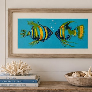 May include: A framed horizontal wall art print featuring two stylized angelfish in shades of yellow, green, and blue against a bright turquoise background, with small white bubbles between them, enclosed in a light brown wood frame with a white mat.