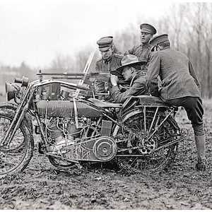 May include: Four soldiers in uniform are riding a motorcycle with a sidecar. The motorcycle is in a muddy field. The soldiers are holding a machine gun.