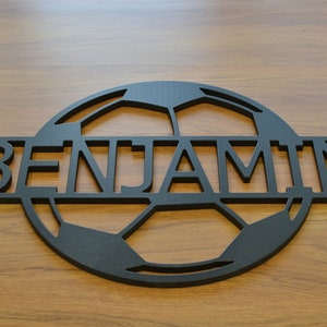 May include: Black wooden sign with a soccer ball design and the name "BENJAMIN" cut out in the center.