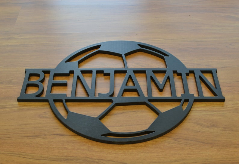 May include: Black wooden sign with a soccer ball design and the name "BENJAMIN" cut out in the center.