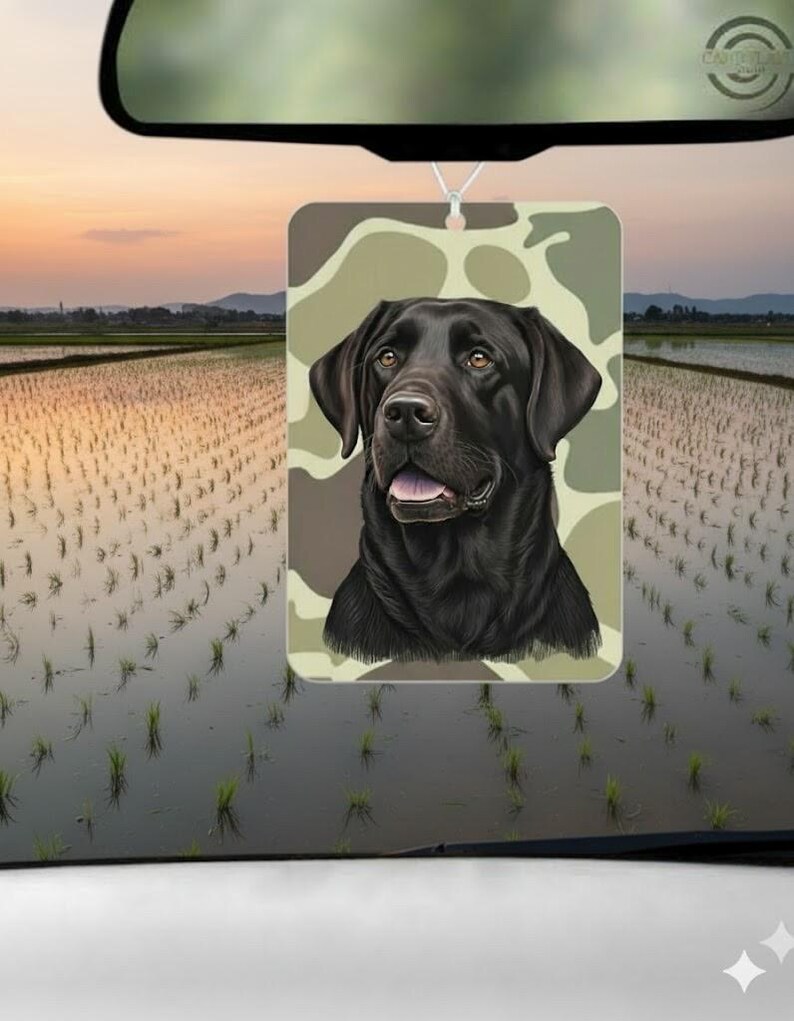 Pode incluir: Ambientador retangular com um Labrador Retriever preto sobre um fundo de camuflagem. O c&atilde;o &eacute; retratado com um estilo detalhado, com foco no seu rosto. Pendurado por um fio, presumivelmente para um carro.