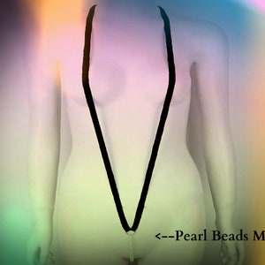 May include: A black string with pearl beads attached to the end. The string is worn as a necklace and is hanging down the front of a person's body. The text "<--Pearl Beads Massage" is visible at the bottom of the image.