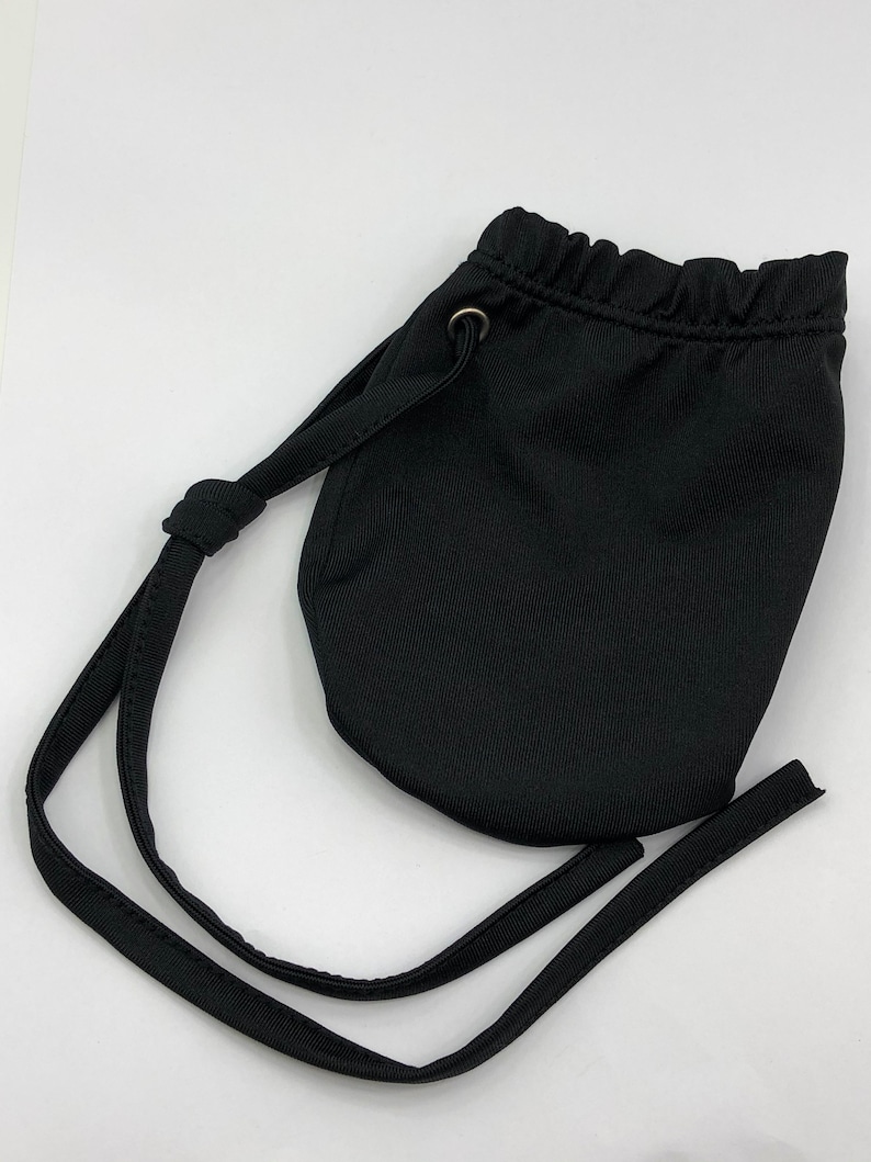 May include: A black drawstring bag with a single strap. The bag is made of a soft, textured fabric.