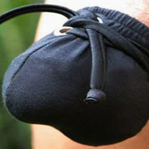 May include: A black fabric pouch with a drawstring closure. The pouch is made of a soft, stretchy material and has a round shape.