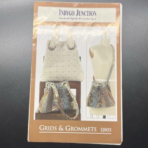 May include: An Indygo Junction sewing pattern envelope titled Grids & Grommets IJ805. The cover displays three handbag designs: a cream-colored quilted tote, a patterned fabric bucket bag with grommets, and a shoulder bag on a mannequin form.