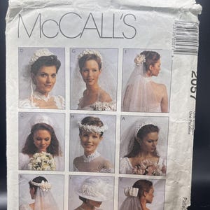 May include: A white McCall's sewing pattern envelope labeled 2057 featuring nine distinct photographic illustrations of bridal headpieces and veils labeled A through I, including various styles of floral crowns, hats, and sheer tulle veils.