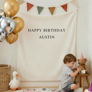 May include: A birthday scene featuring balloons, a banner, and a child. The banner says "HAPPY BIRTHDAY AUSTIN." A round rug with a colourful design is on the floor. A teddy bear wears a party hat.