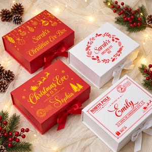 Puede incluir: Cuatro cajas de regalo rectangulares con tapas y cierres de cinta. Dos son rojas con texto dorado Sarah's Christmas Eve Box y Christmas Eve Box Special Delivery for Sophia. Dos son blancas con texto rojo Sarah's Christmas Eve Box y North Pole Express Delivery for Emily.