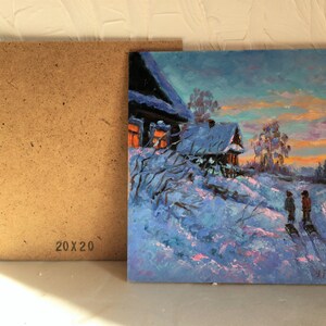 May include: A painting of a snowy winter scene with two houses, one with lit windows, and two figures walking in the snow. The sky is a vibrant blue with pink and orange hues. The painting is 20 inches by 20 inches.