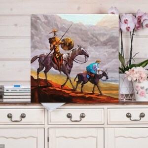 May include: A painting of two figures on horseback riding through a mountainous landscape. The figures are wearing colorful clothing and the horses are brown and white. The background is a hazy blue and gray.