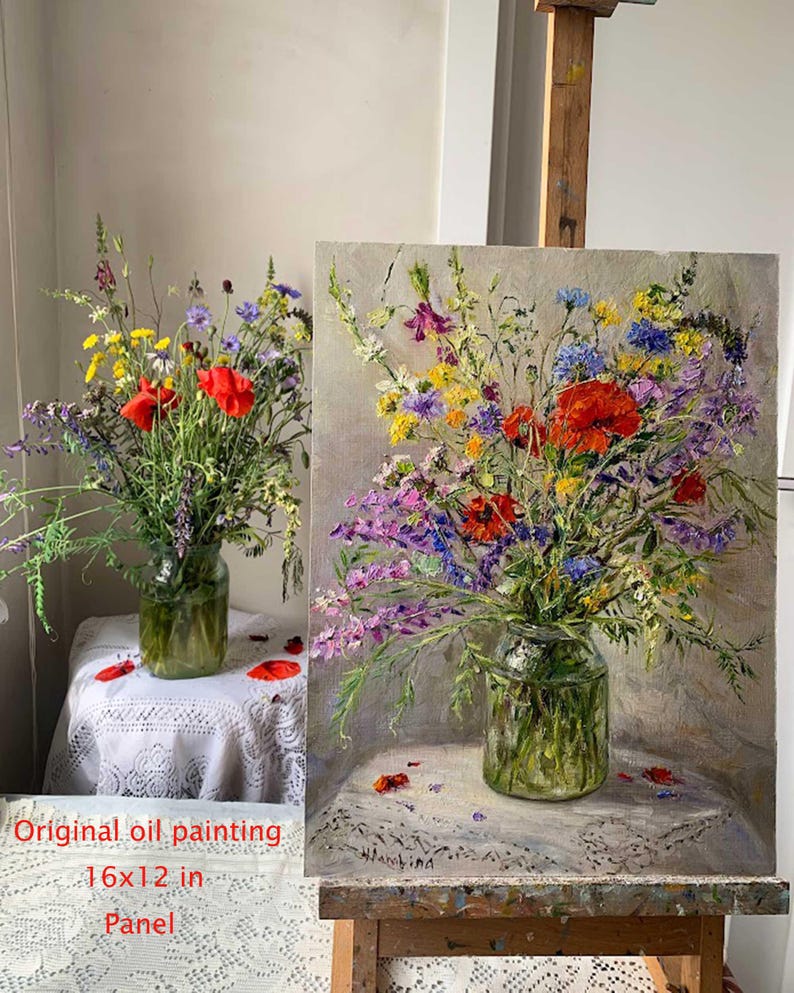 May include: Original oil painting of a vibrant floral arrangement in a glass jar, featuring red poppies, purple, yellow, and blue wildflowers. The artwork is 16x12 inches on a panel, displayed on an easel and table with a lace tablecloth.