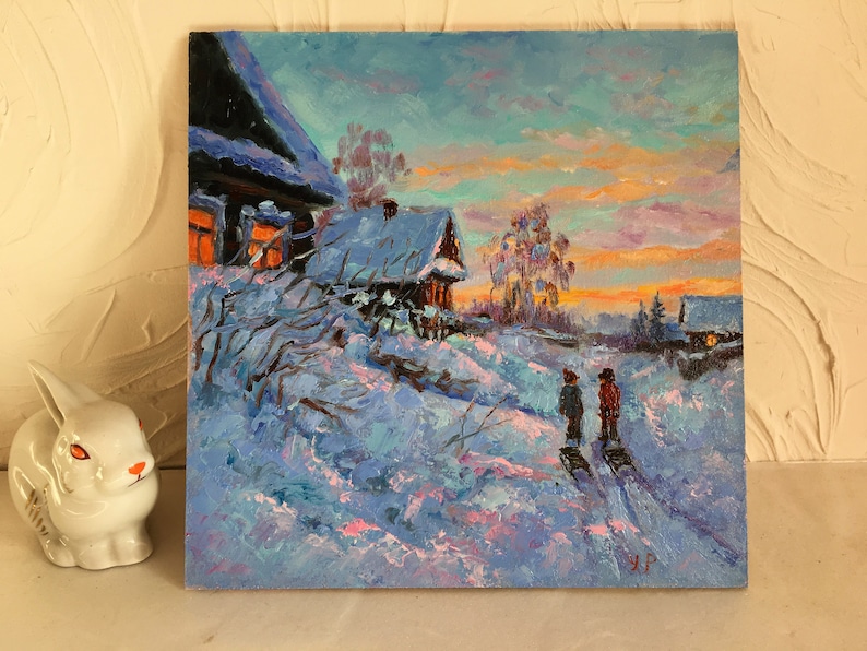 May include: A painting of a snowy winter scene with two figures walking in the distance. The painting features a small wooden house with a lit window, a snow-covered field, and a colorful sunset sky.