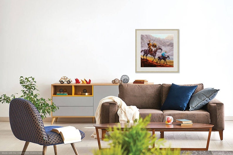 May include: A framed painting of two people on horseback riding through a desert landscape. The painting is in a light brown frame and is hanging on a white wall.