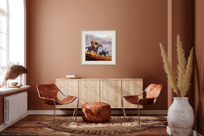 May include: A framed painting of two figures on horseback riding through a misty landscape. The figures are wearing traditional clothing and the horse in the foreground is brown. The painting is set against a brown wall with a wooden cabinet and two chairs in the foreground.