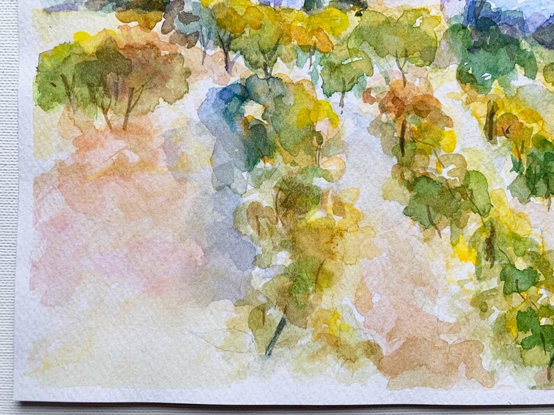 Op de afbeelding: Aquarel schilderij van een landschap met bomen en bladeren in tinten groen, geel en bruin. Het kunstwerk heeft een zachte, impressionistische stijl met een licht, luchtig gevoel. De lucht is een mix van blauw en wit.