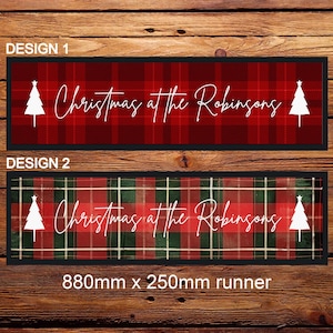 May include: Two designs for a Christmas bar runner. The first design features a red and black tartan pattern with white Christmas trees and the text "Christmas at the Robinsons". The second design features a green and red tartan pattern with white Christmas trees and the text "Christmas at the Robinsons". Both runners are 880mm x 250mm.