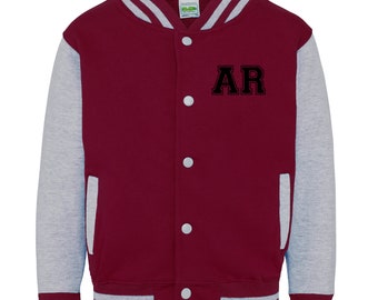 Op de afbeelding: Bordeauxrode en grijze varsity jas met witte strepen op de mouwen en de kraag. De jas heeft een knoopsluiting en een zak aan de linkerkant. De letters "AR" zijn geborduurd op de voorkant van de jas.