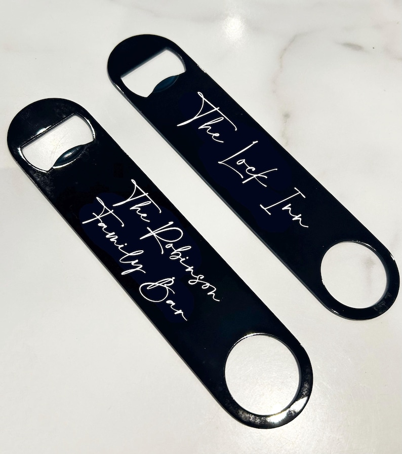 May include: Two black metal bottle openers with white text. The top opener says "The Lock Inn" and the bottom opener says "The Robinson Family Bar".