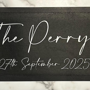 May include: Black wooden sign with white text that reads "The Perrys" and "27th September 2025".