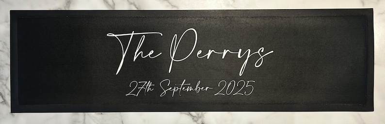 May include: Black wooden sign with white text that reads "The Perrys" and "27th September 2025".
