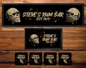 May include: A black bar runner with a gold skull design and the text "STEVE'S RUM BAR EST 2023". The runner is 880mm x 250mm. There is also a smaller version of the runner that is 440mm x 250mm. There are four coasters with the same design as the runner.