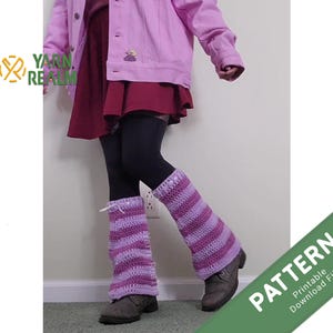 Puede incluir: Calentadores de piernas de ganchillo a rayas moradas y lavanda. Se llevan con leggings oscuros y botas grises. La imagen también muestra una chaqueta rosa y un vestido rojo. El logotipo de Yarn Realm es visible en la esquina superior izquierda.