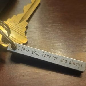 May include: A silver keychain with a bar engraved with the words "I love you, forever and always".
