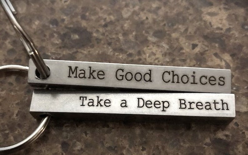 May include: A silver keychain with two metal bars. The top bar reads "Make Good Choices" and the bottom bar reads "Take a Deep Breath".