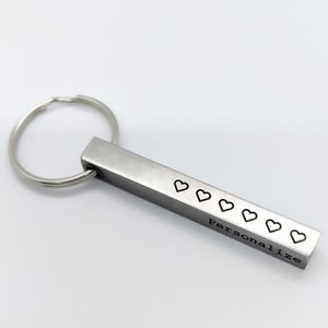 May include: Silver metal keychain with a bar that has six hearts and the word "Personalize" engraved on it.