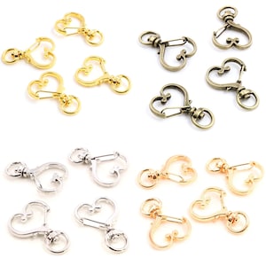 May include: Assortment of heart-shaped metal keychains in gold, silver, and bronze finishes. Each keychain features a swivel clasp and a spring-loaded hook.
