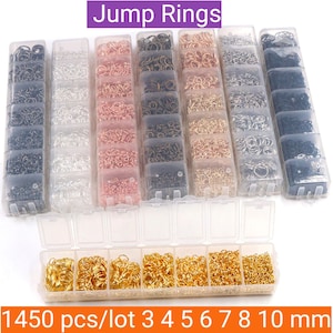 Puede incluir: Un conjunto de anillas de salto de diferentes tamaños y colores, incluyendo negro, plata, oro y oro rosa. Las anillas están organizadas en contenedores de plástico transparente, cada contenedor contiene un tamaño diferente. Los contenedores están dispuestos en dos filas, la fila superior contiene los tamaños más pequeños y la fila inferior contiene los tamaños más grandes. El texto "Jump Rings" está impreso en morado en la parte superior de la imagen. El texto "1450 pcs/lot 3 4 5 6 7 8 10 mm" está impreso en la parte inferior de la imagen.