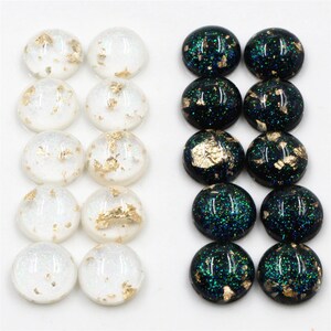 May include: A set of 18 round cabochons, 9 white with gold flecks and 9 black with green glitter and gold flecks.