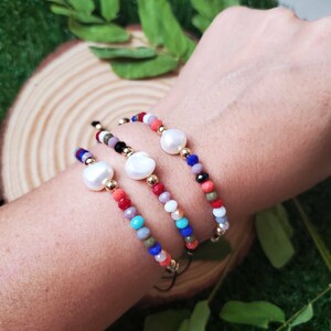Puede incluir: Tres pulseras de cuentas coloridas con detalles de perlas. Cada pulsera presenta un esquema de color diferente, que incluye rojo, azul, verde y naranja.