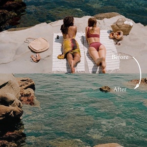 May include: Two people in swimsuits are laying on towels on a sandy beach. The beach is next to a body of water. There is a wicker basket with fruit in it.