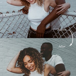 May include: A couple poses in front of a white brick wall. The woman is wearing a white tank top and black pants with a silver chain belt. The man is wearing a white t-shirt. They are both smiling and laughing. The couple is standing in front of a chain link fence.