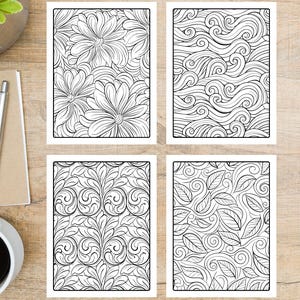 May include: Four black and white coloring pages with floral and abstract designs. The pages feature detailed line art of flowers, swirling waves, and leafy patterns. The pages are rectangular and set on a wooden surface.