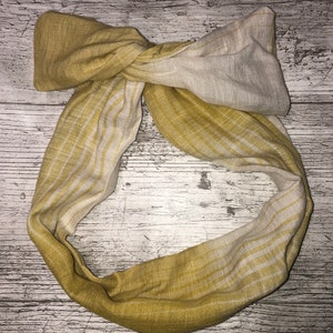 May include: A yellow and white striped fabric headband with a knotted bow.