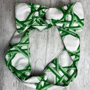 May include: A white headband with a green bamboo pattern. The headband is tied in a knot at the top.