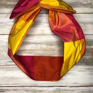 May include: A red, orange, and yellow plaid headband with a knotted bow.