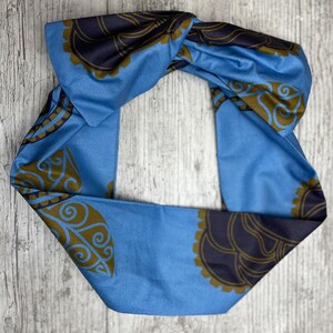May include: A blue headband with a knotted design and a brown and black paisley pattern.