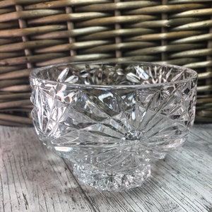 May include: A clear glass bowl with a cut-glass design. The bowl has a wide, round base and a flared rim.