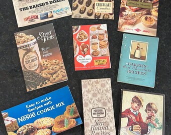 May include: A collection of vintage recipe books featuring various chocolate and dessert recipes. The books have colorful covers with images of chocolate candies, cookies, and cakes. The titles include "The Baker's Dozen", "Sweet Treats", "Chocolate Candies", "Holiday Desserts", "Baker's Best Chocolate Recipes", "Nestlé Hot Cocoa Mix Year Round Recipes", and "Hershey's Index Recipe Book".