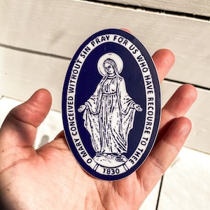 以下が含まれることがあります： 聖母マリアの画像と「O Mary conceived without sin pray for us who have recourse to thee 1930」というテキストが書かれた青と白の楕円形のステッカーです。
