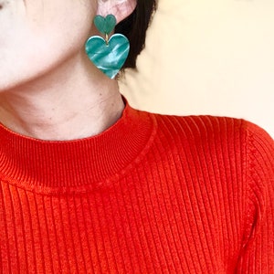 May include: A pair of green heart-shaped earrings with a marbled pattern. The earrings are made of two hearts stacked on top of each other.